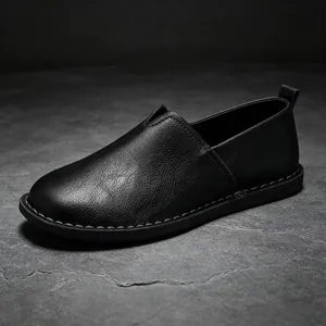 Macro view showing the fine texture of black handmade leather slip-on shoes with soft sole