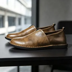 Close-up side view of vintage brown leather slip-on shoes with handmade stitching detail
