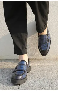 Detail of men's navy blue crocodile texture leather shoes with buckle and thick sole.