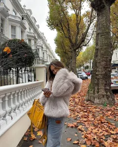 Detailweergave van een lichtgrijze faux fur jas met capuchon voor dames in de herfst