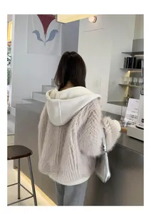 Rückansicht einer flauschigen Kunstpelzjacke mit großer Rippstrickkapuze im Café.