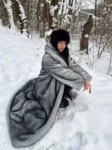 Langer grauer Kunstpelzmantel aus Fuchsimitat für Damen in verschneiter Winterlandschaft.