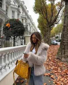 Cozy beige faux fur hooded jacket styled with blue jeans on a scenic autumn street.