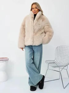 Frau in beigem Kunstpelzmantel aus Fuchspelzimitat und blauen Jeans mit weitem Bein.