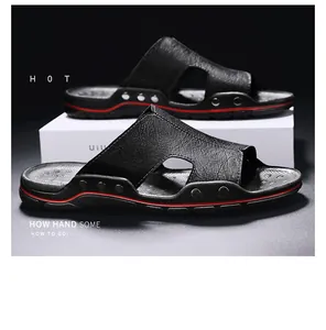 Close-up van zwarte leren heren slippers met rode accenten op donkere basis.