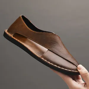 Close-up of brown handmade leather slip-on sandal with hollow design and stitching