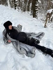 Detaillierte Außenansicht einer Frau in einem langen grauen Kunstpelzmantel im tiefen Schnee