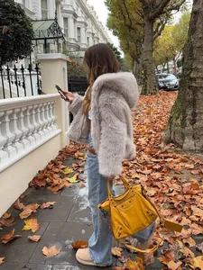 Modische hellviolette Webpelzjacke mit Kapuze für herbstliche Straßenmode vor Herbstlaubhintergrund