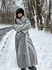 Eleganter langer Damen Kunstpelzmantel aus Fuchsimitat in einer verschneiten Waldlandschaft.