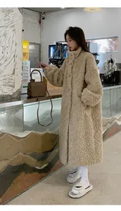 Side view of long beige plush lamb wool coat worn by a model in a cozy cafe setting