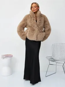 Elegante Frau in beiger Kunstpelzjacke und langem schwarzem Rock vor einem weißen Hintergrund