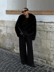 Eleganter schwarzer Kunstpelzmantel mit Schalkragen in einem urbanen Ambiente gestylt