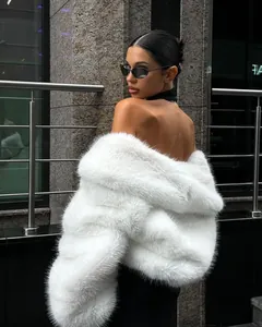 Detailed close-up of a premium white faux fur coat on an elegant model outdoors