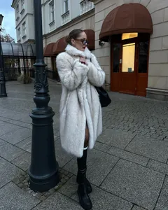 Donna elegante in un lungo cappotto di ecopelliccia bianca in una strada europea