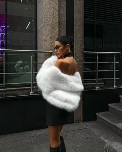 Detail shot of a luxurious white faux fur coat styled with an urban chic outfit