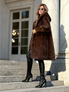 Elegant long brown faux fur hooded coat for women styled with black leather boots.
