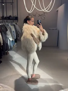 Close-up detail of a shaggy beige faux fur coat worn in a boutique mirror selfie