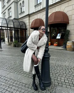 Elegante cappotto lungo in ecopelliccia bianca indossato da una modella di moda in città.