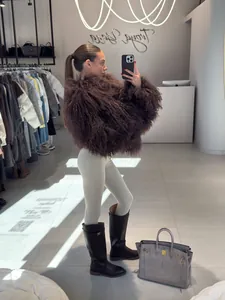 Detailed view of a fluffy brown long hair faux fur coat worn in a boutique setting