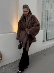 Elegante Frau in einem braunen Kunstpelzmantel mit Gürtel und Reverskragen für den Winter.