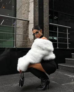 Fashion model wearing a luxury white faux fur cropped coat in an urban street setting