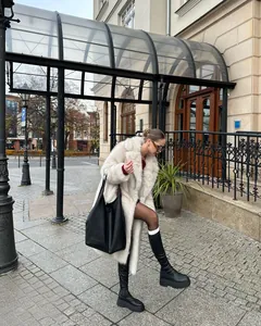 Elegante cappotto lungo in ecopelliccia bianca con stivali neri con plateau moderno