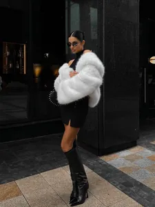 Fashionable woman wearing a luxurious white faux fur coat in a stylish urban city street setting.