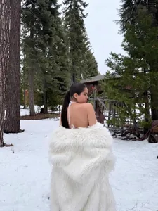 Elegant long white faux fur coat providing winter warmth in a snowy forest setting