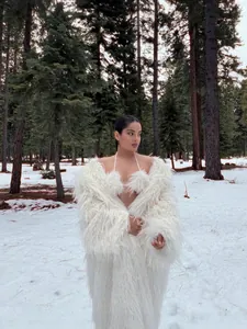 Elegant extra long white faux fur coat for women in a snowy winter forest setting