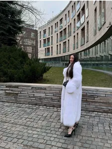 Elegante cappotto lungo in ecopelliccia bianca indossato da una modella all'aperto