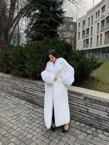 Elegante lungo cappotto in ecopelliccia bianca in un moderno contesto all'aperto