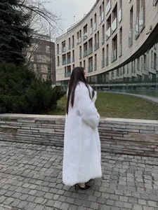 Vista laterale di un lussuoso lungo cappotto in finta pelliccia bianca in città moderna