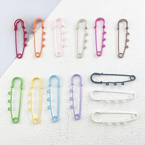 Macro detail of 13 assorted colorful 6cm safety pins with three loops for DIY jewelry.