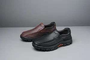 Detailed view of men's slip-on leather loafers in black and brown with orange stitching