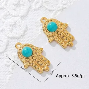 Close-up of golden Hamsa hand pendant with turquoise stone and size dimensions
