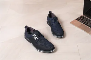 Detailansicht von marineblauen Herren-Sneakern mit Webmuster auf Holzboden