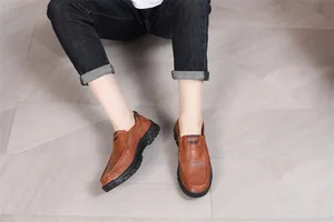Vue détaillée de mocassins en cuir marron portés avec un jean sombre sur le sol