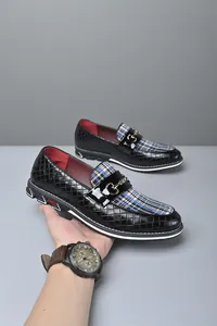 Vista detallada de mocasines negros para hombre con empeine de cuadros y hebilla.