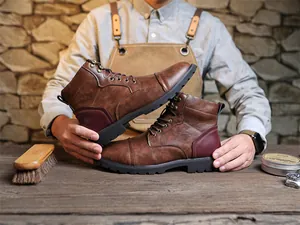 Detailed view of vintage brown leather men's Martin boots in a rustic workshop setting