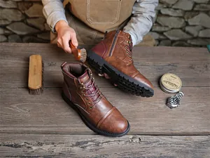 Close-up of vintage brown leather Marton boots during professional shoe care session.