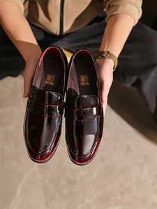Nahaufnahme eleganter burgunderfarbener Lackleder-Loafer für Herren mit Hochglanz-Finish.