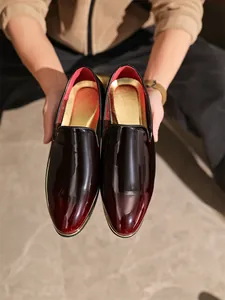 Close-up detail of premium glossy gradient burgundy red men's patent leather loafers