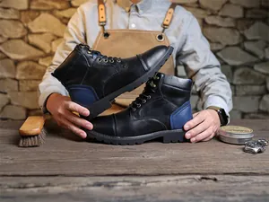 Close-up of retro black leather Martin boots with blue heel detail in a rustic workshop setting.