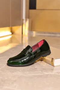 Nahaufnahme eines dunkelgrünen Lackleder-Loafers für Herren auf einem Marmorboden