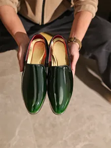 Detailed close-up of glossy green patent leather men's loafers with gold metallic trim