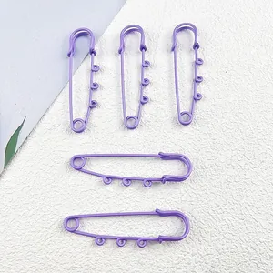 Macro detail of five purple painted metal safety pins with DIY hanging loops