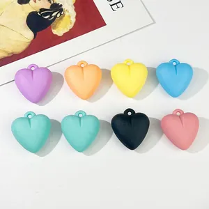 Detailed macro view of colorful matte acrylic heart charms with hanging holes for DIY crafts