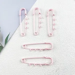 Detailed view of five 6cm pink painted safety pins with three loops for DIY crafts