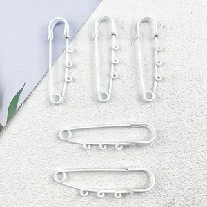 Detailed view of white lacquered large safety pins for DIY jewelry and bag accessories