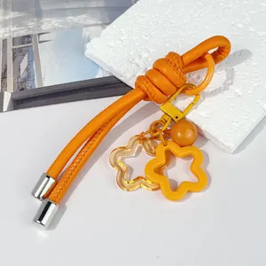 Detalle del llavero de cuerda de cuero naranja DIY con colgantes de estrella naranja.